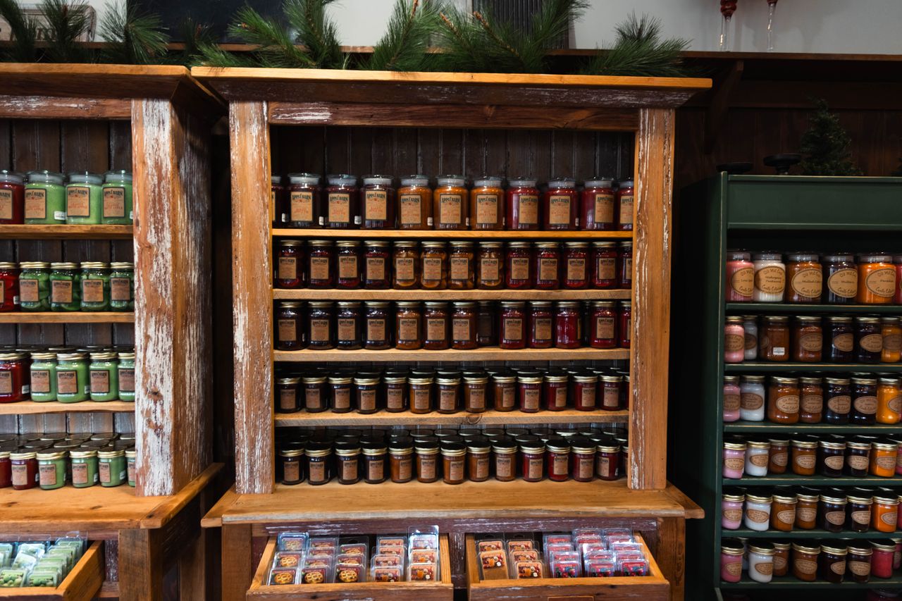 about-02 Rustic wooden shelves displaying a variety of jarred products in a cozy store setting.