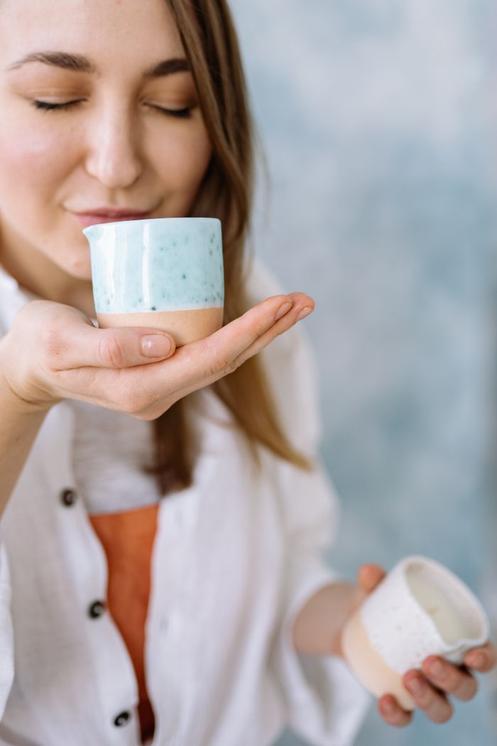 gallery-3 Smiling woman savoring aroma from handmade ceramic mug, eyes closed in bliss.